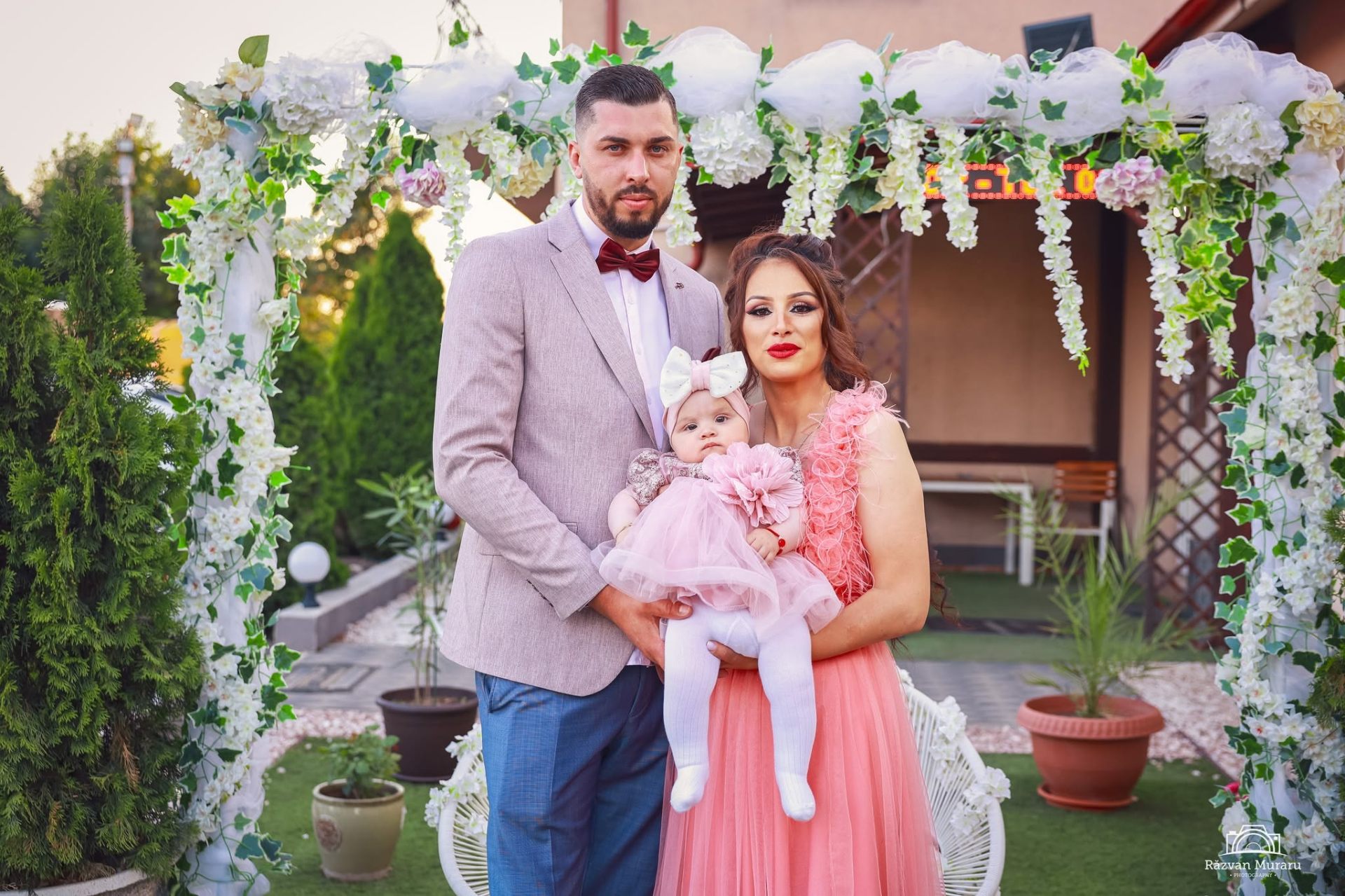 Familie sub arcada decorată cu flori la botez