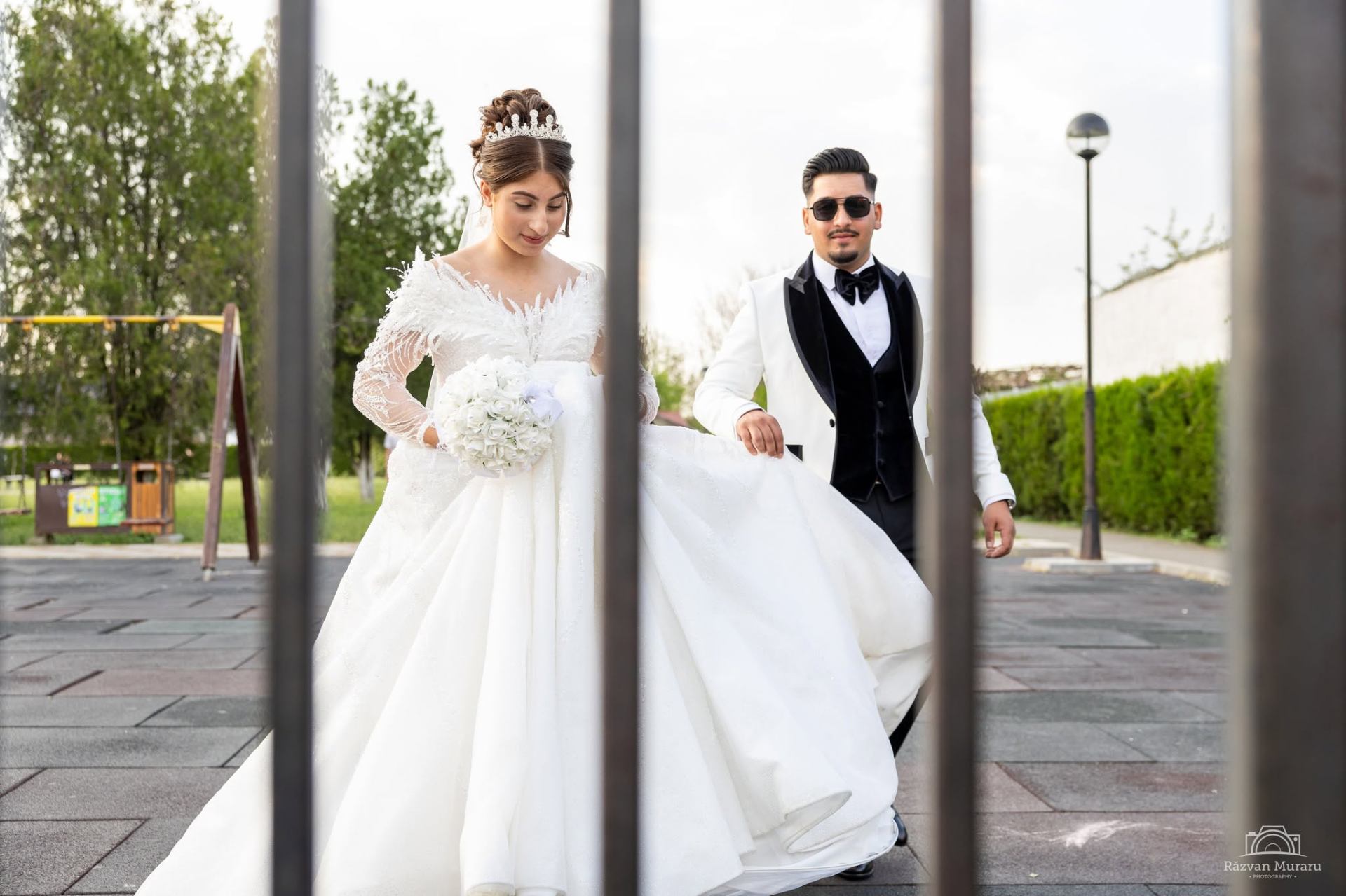 Mireasă cu trena lungă printre porțile metalice